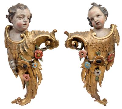 A pair of large carved angels’ heads mounted on ornaments with floral garlands, - Works of Art